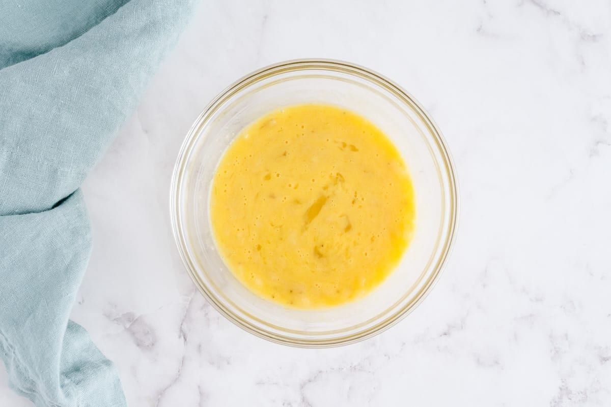 Ovos e bananas misturados em uma tigela de vidro para misturar.