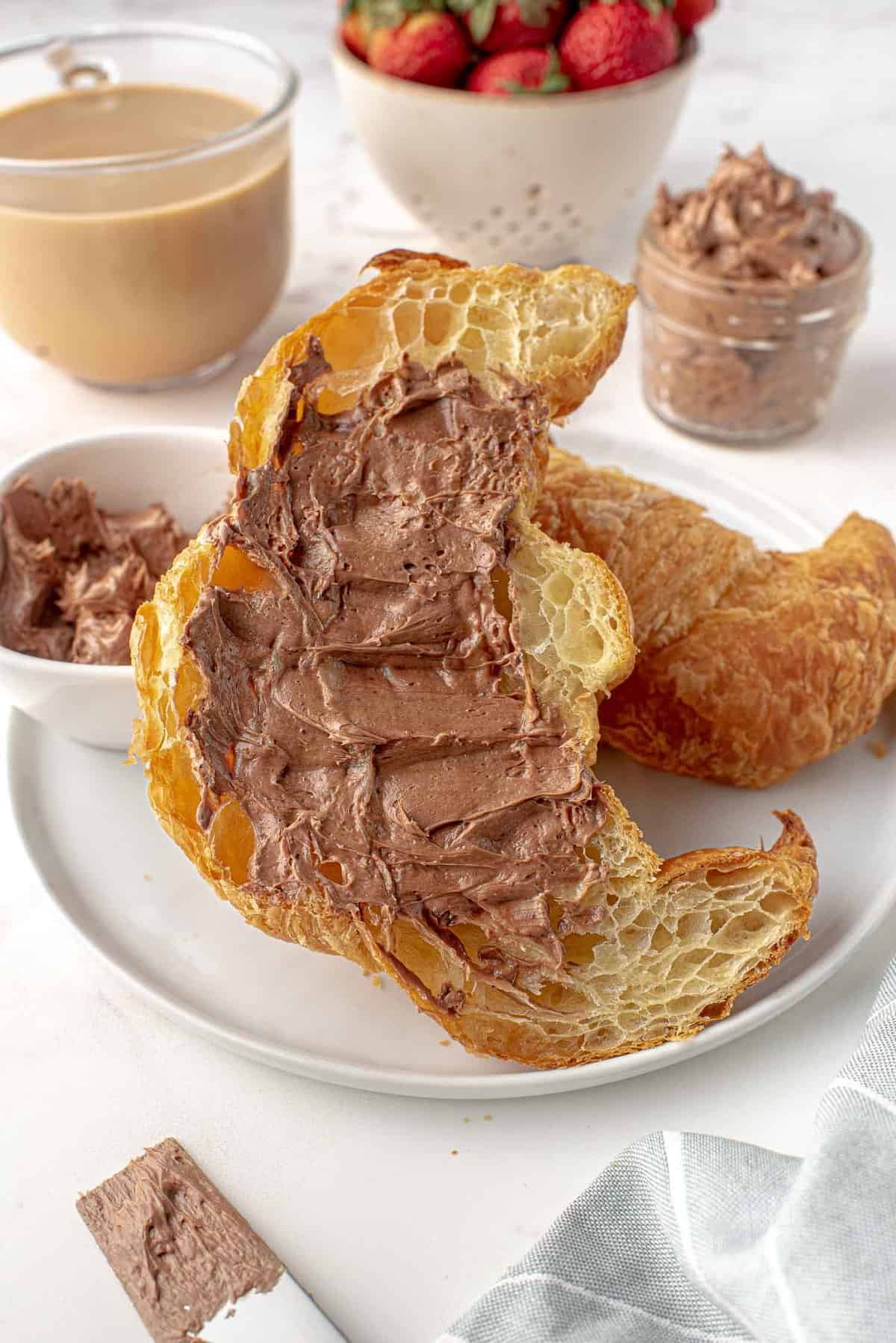 Manteiga com cacau em pó espalhada em um croissant.