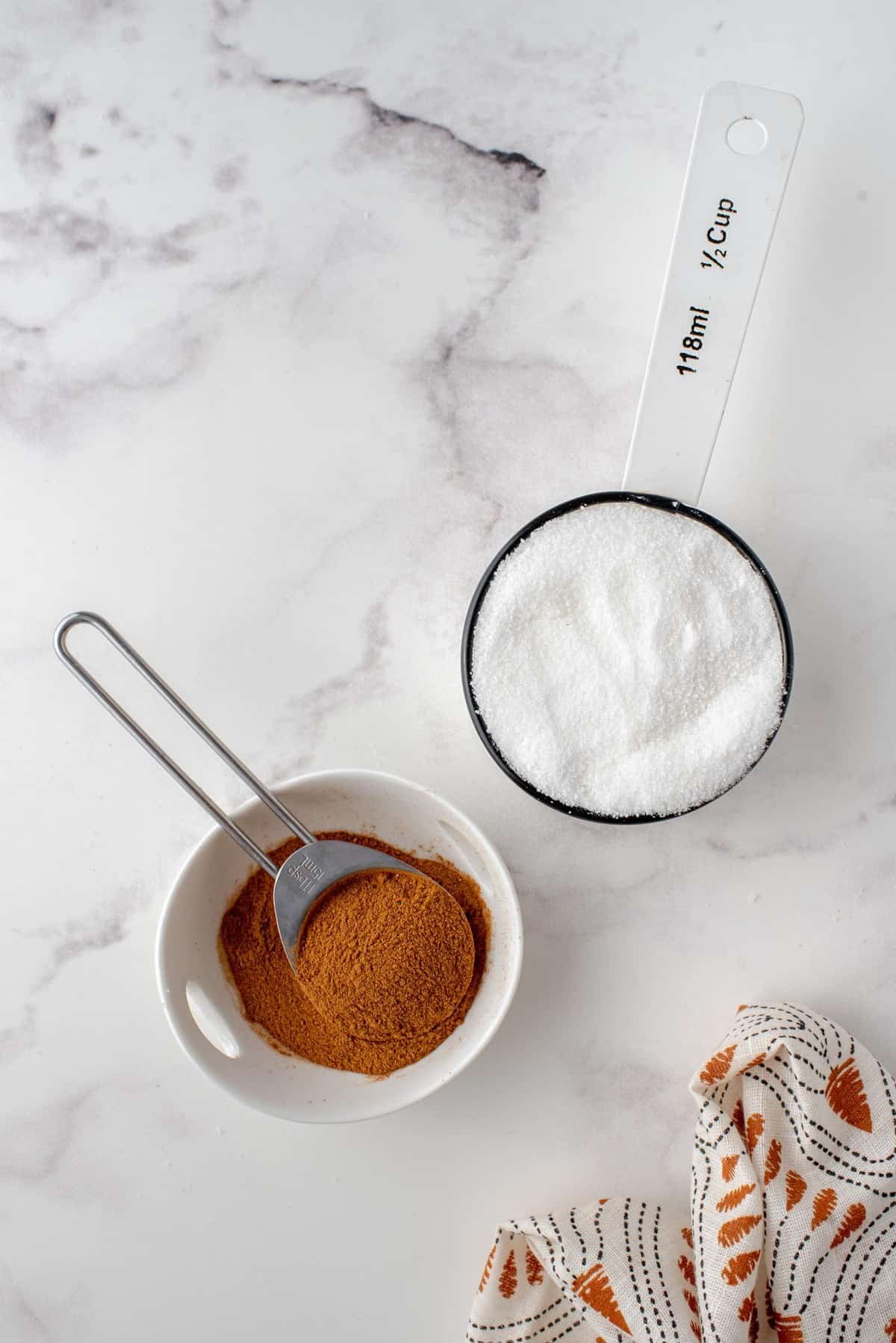 Canela e açúcar em tigelas separadas.