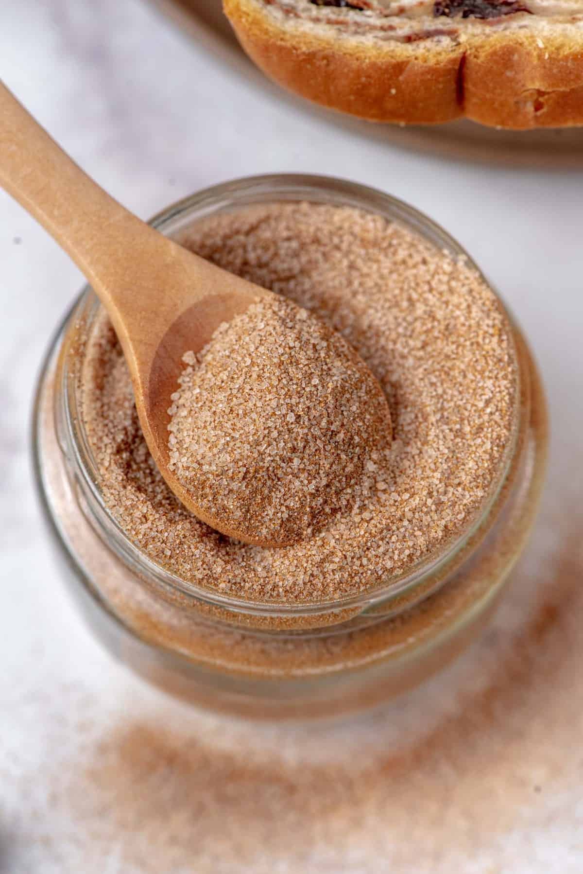 Visão aérea de açúcar e canela em um pote com uma colher de madeira.