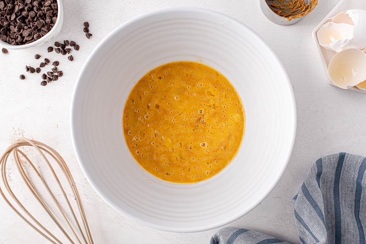 Ingredientes úmidos em uma tigela de mistura branca.