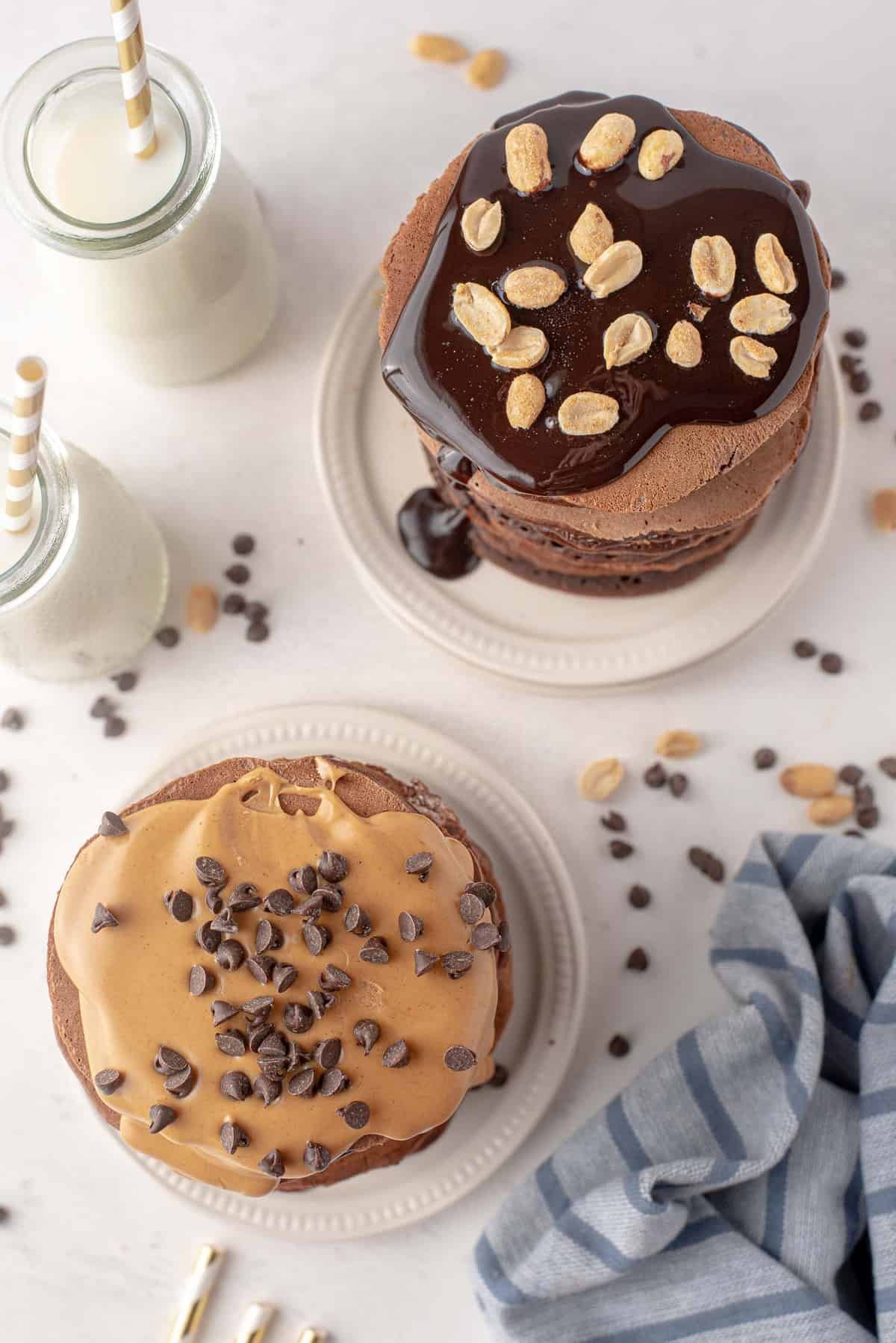 Visão aérea de duas pilhas de panquecas de chocolate cobertas com manteiga de amendoim e amendoins.