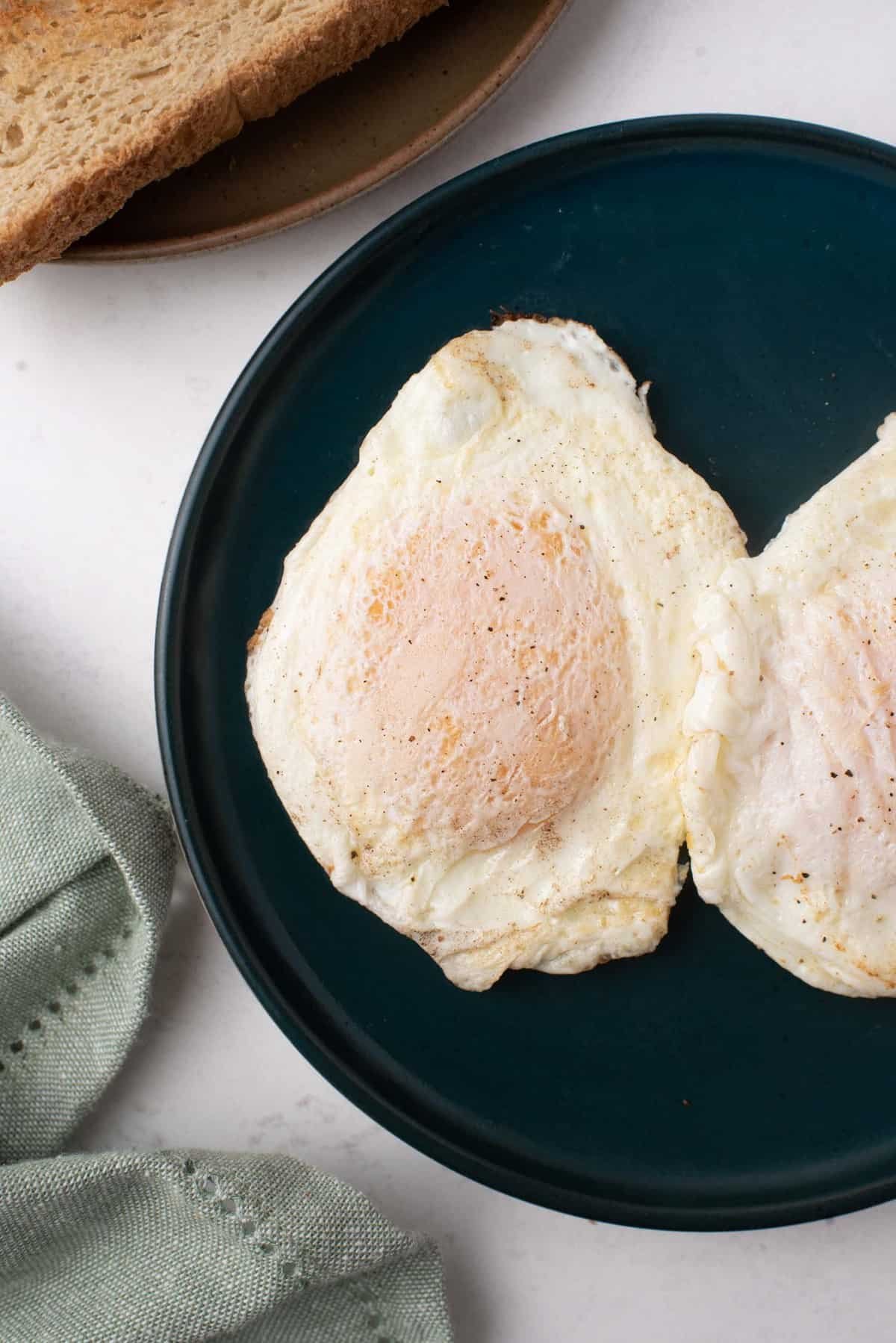 Dois ovos em um prato de cor escura.