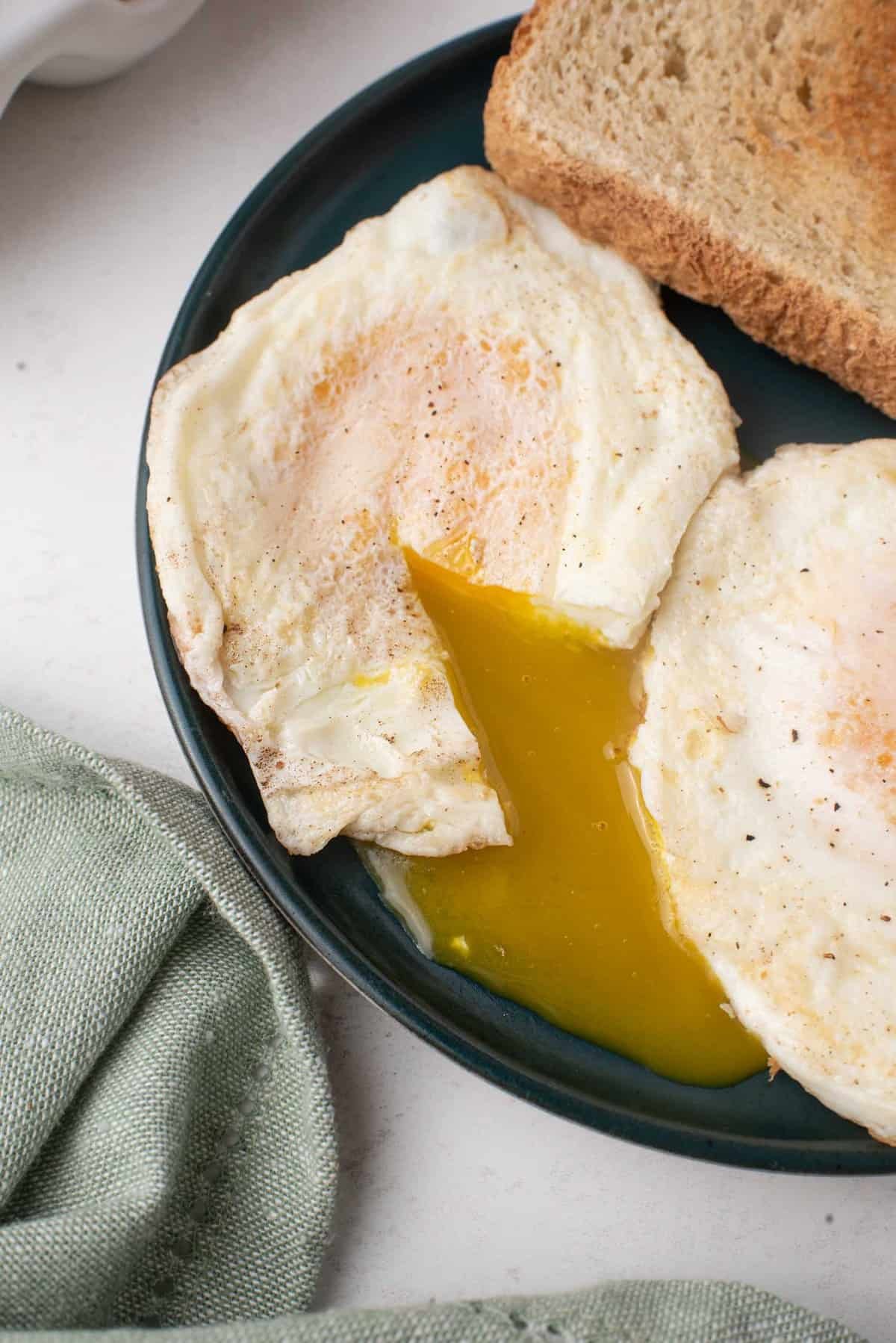 Dois ovos cozidos ao ponto, gema de um escorrendo no prato.