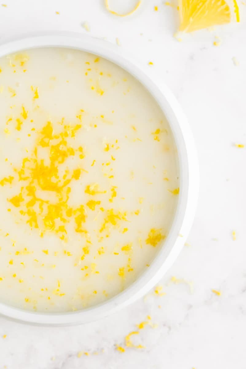 Glacê em uma tigela branca pequena, polvilhada com raspas de limão.