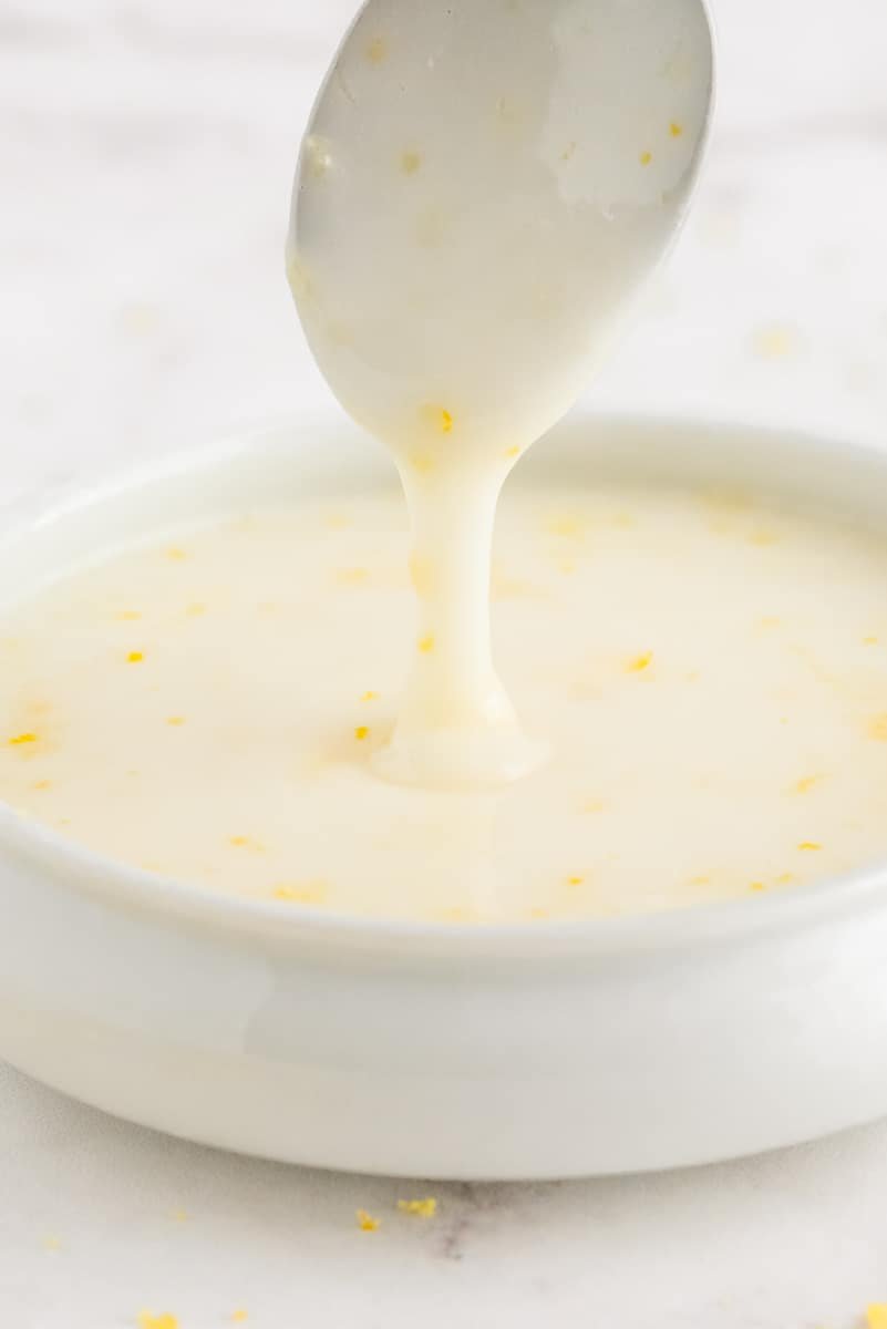 Glacê em uma tigela pequena com uma colher pingando mais glacê.