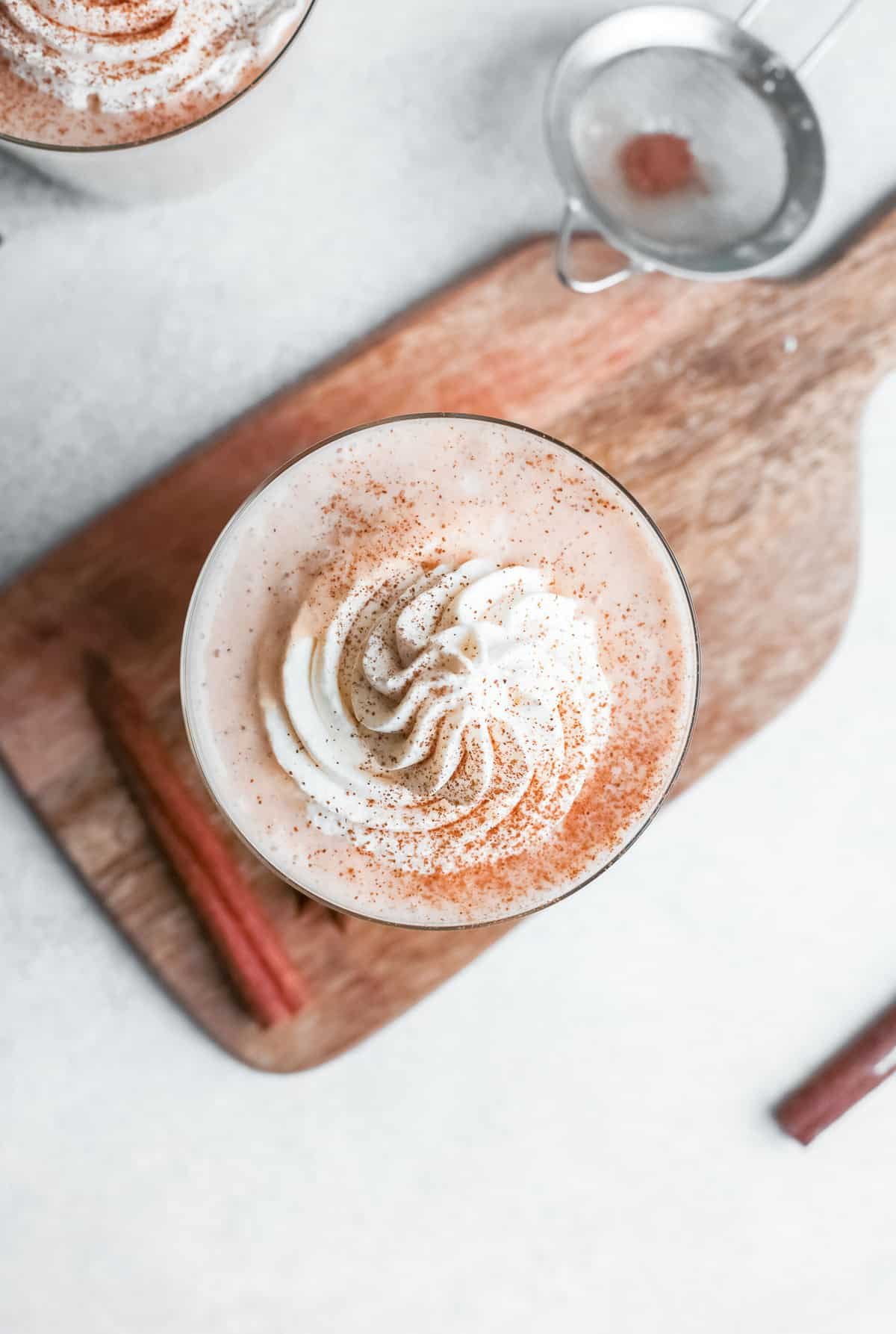 Vista aérea de um smoothie em uma tábua de madeira, coberto com chantilly.