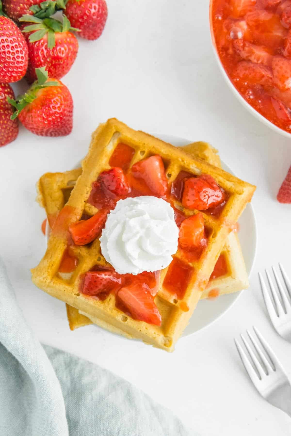 Waffles cobertos com morangos e chantilly.