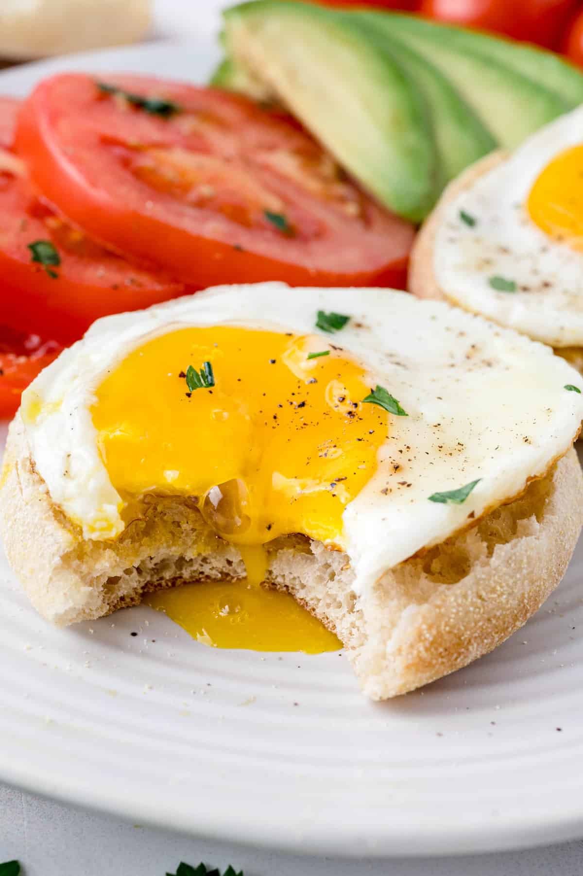 Ovo frito líquido em cima de um muffin inglês torrado.