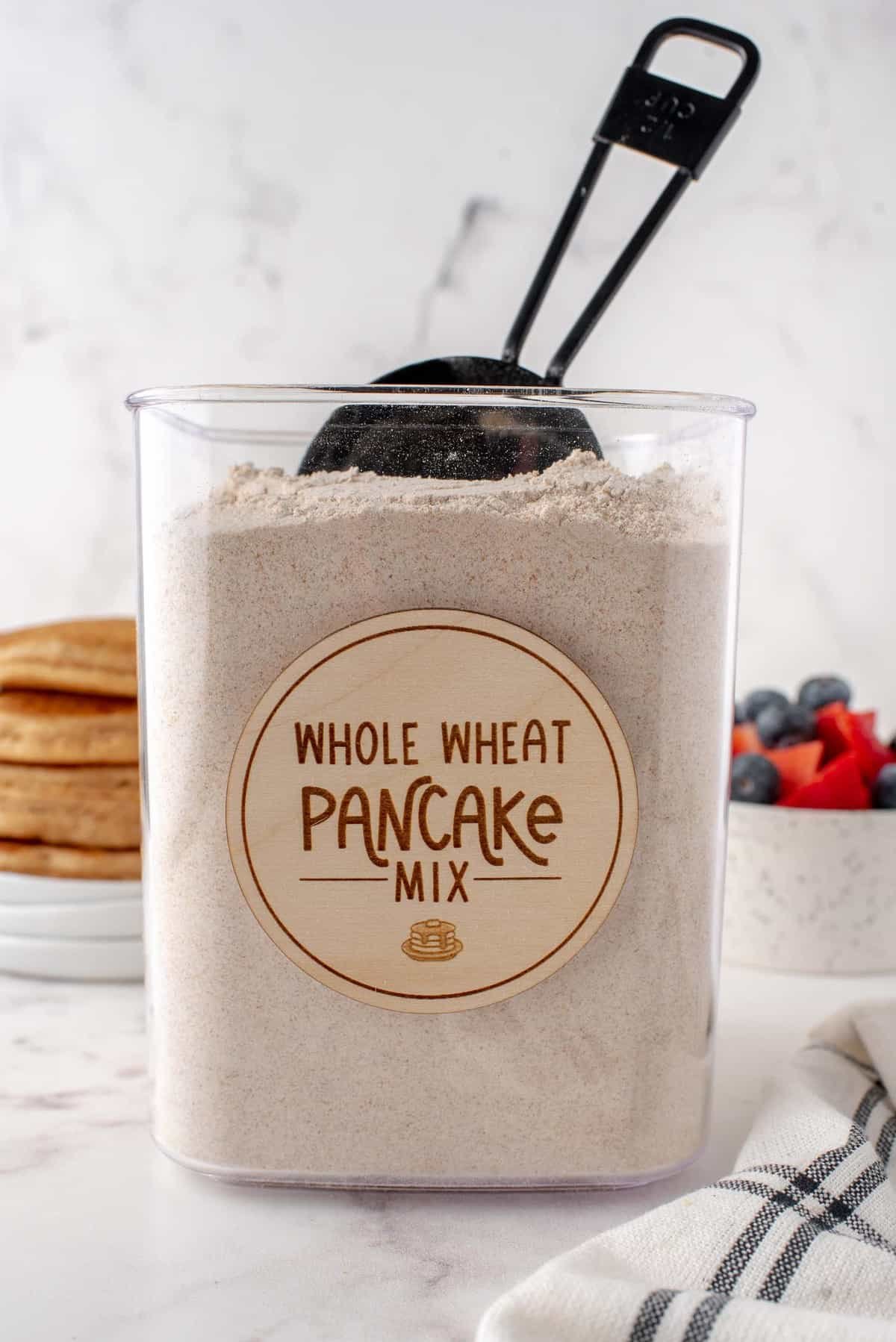 Mistura de panquecas de trigo integral em um frasco com tampa e colher.
