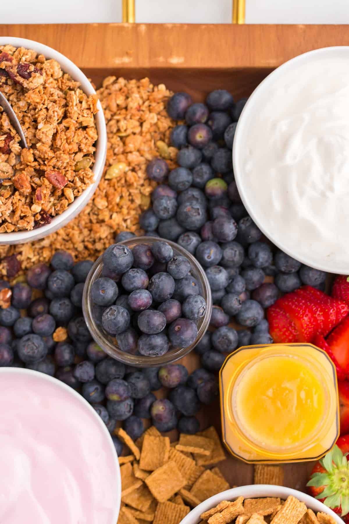 Mirtilos, iogurte, granola e creme de limão em um prato.