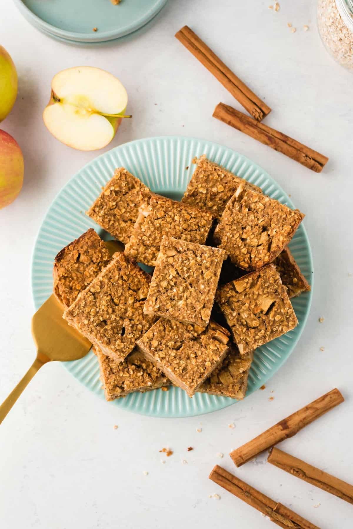 Bandeja azul cheia de quadrados de aveia assada. Pauzinhos de canela na imagem.