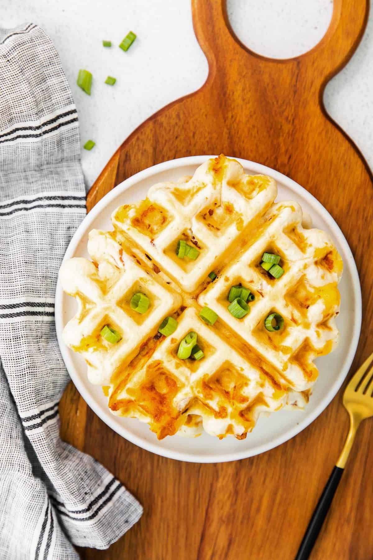 Waffle de bacon e cheddar em uma tábua de cortar de madeira.