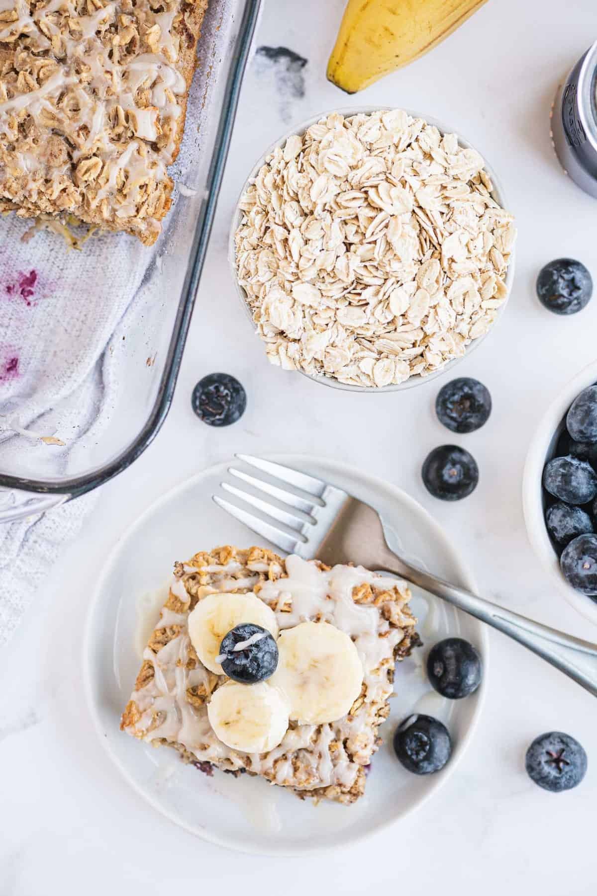 Visão aérea de uma fatia de aveia assada ao lado de uma assadeira de aveia.