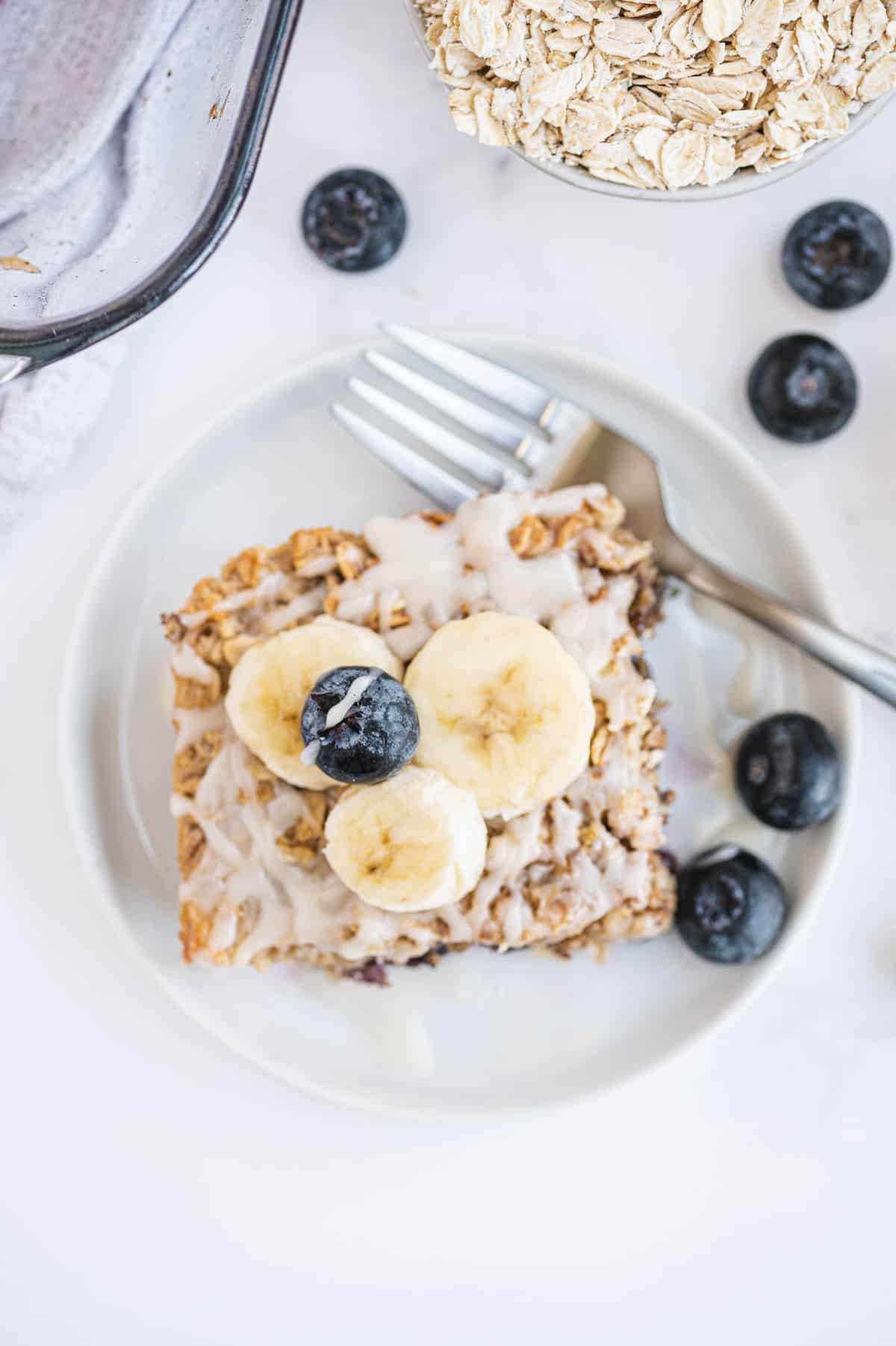 Visão aérea de um quadrado de panqueca de aveia assada com banana e glacê.