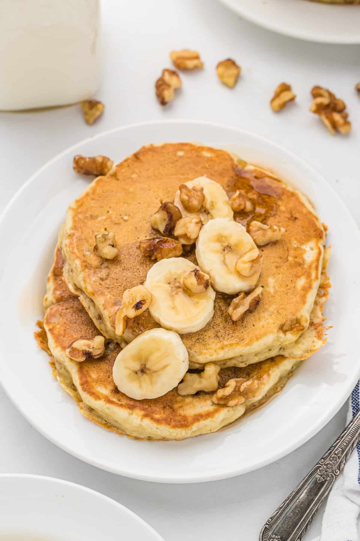 Panquecas de banana e nozes em um prato branco.