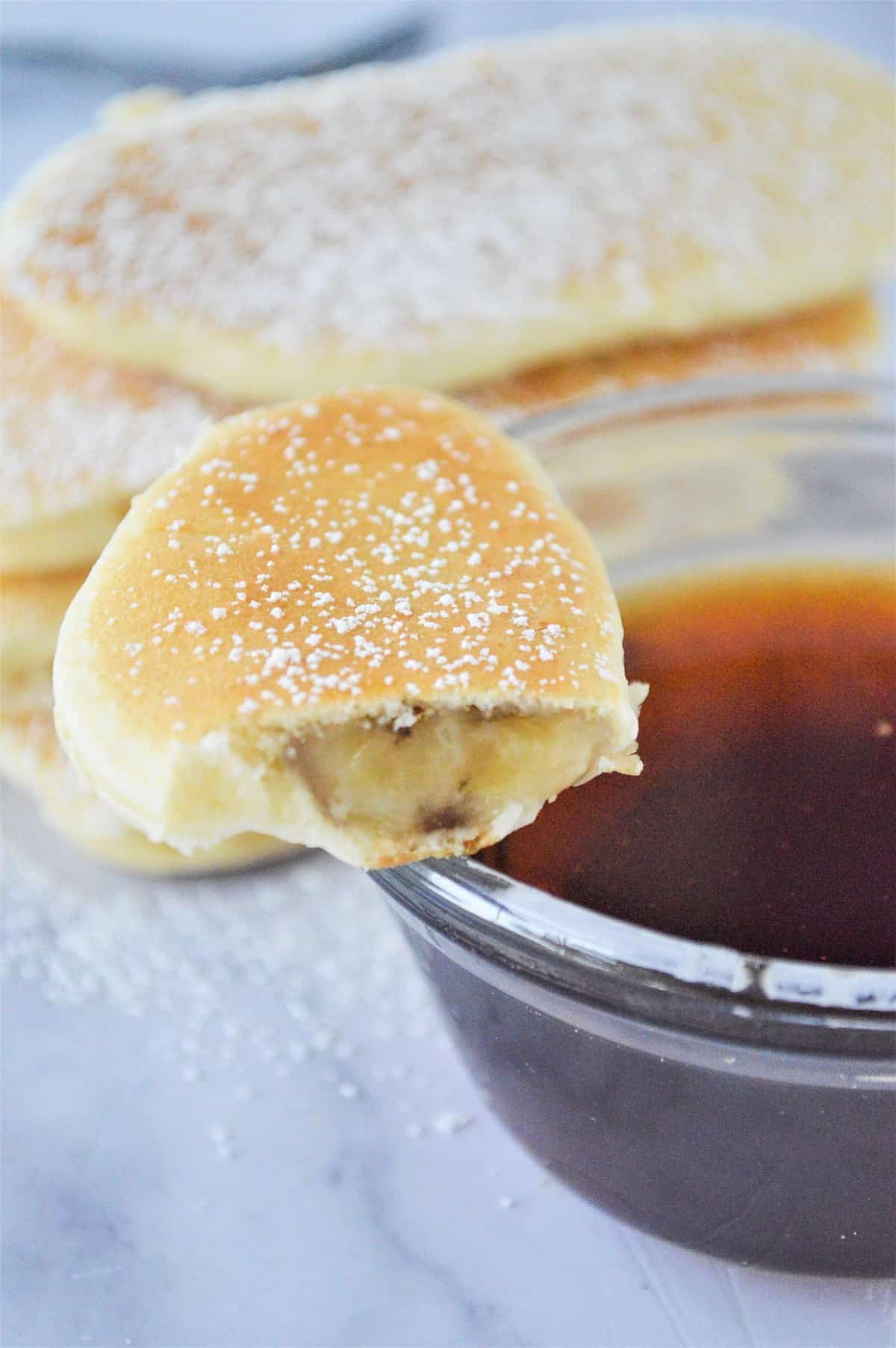 Metade de uma panqueca de banana em uma tigela de xarope.