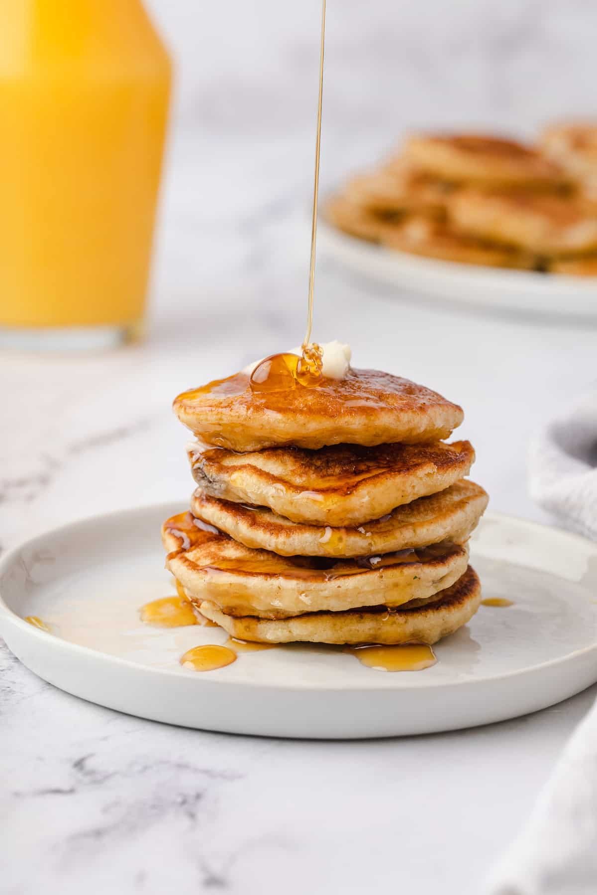 Xarope sendo derramado sobre as panquecas de banana.