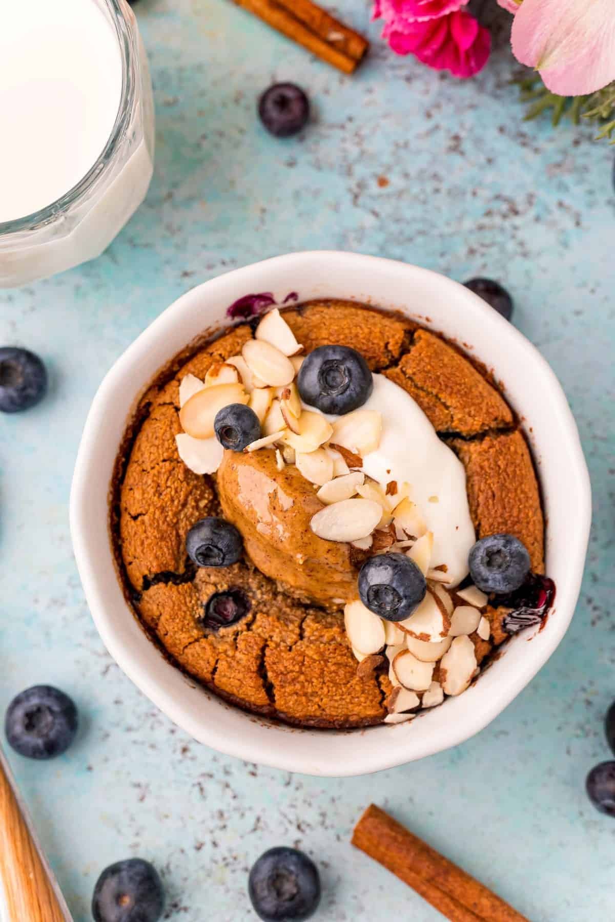 Vista aérea de aveia assada com mirtilos coberta com iogurte, mirtilos, amêndoas.