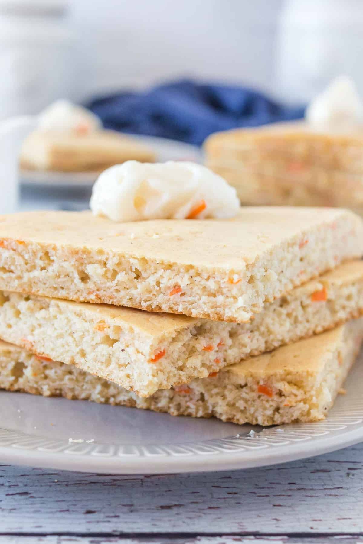Panquecas de cenoura cortadas em quadrados, empilhadas em três e cobertas com manteiga.