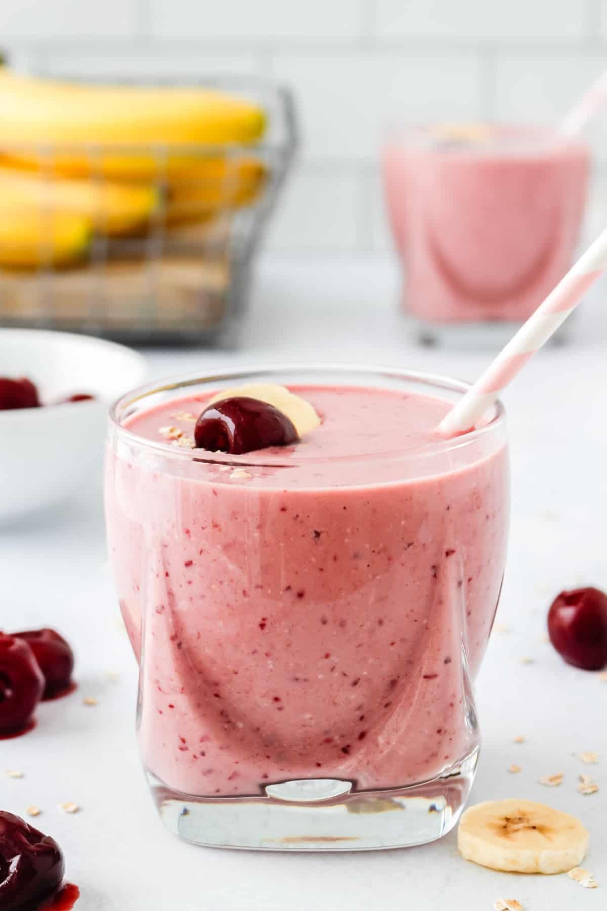 Smoothie de cereja em um copo curto transparente, outro em segundo plano.