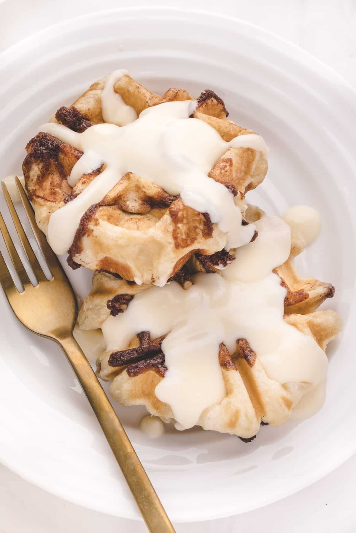 Waffles de rolo de canela com cobertura em um prato branco.