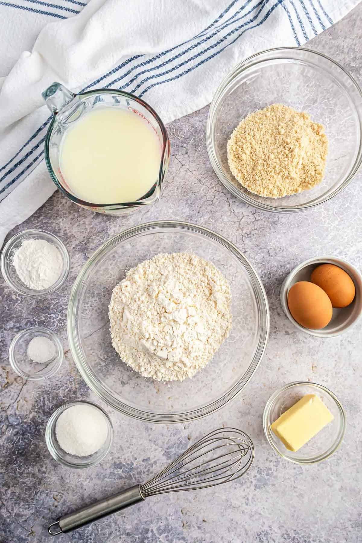 Visão aérea de ingredientes em tigelas em um fundo branco e cinza.
