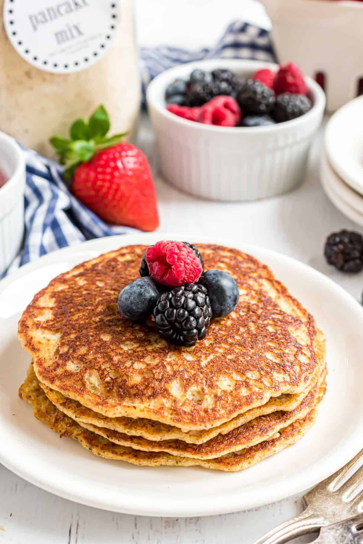 Panquecas keto com um pote de mistura de panqueca ao fundo.