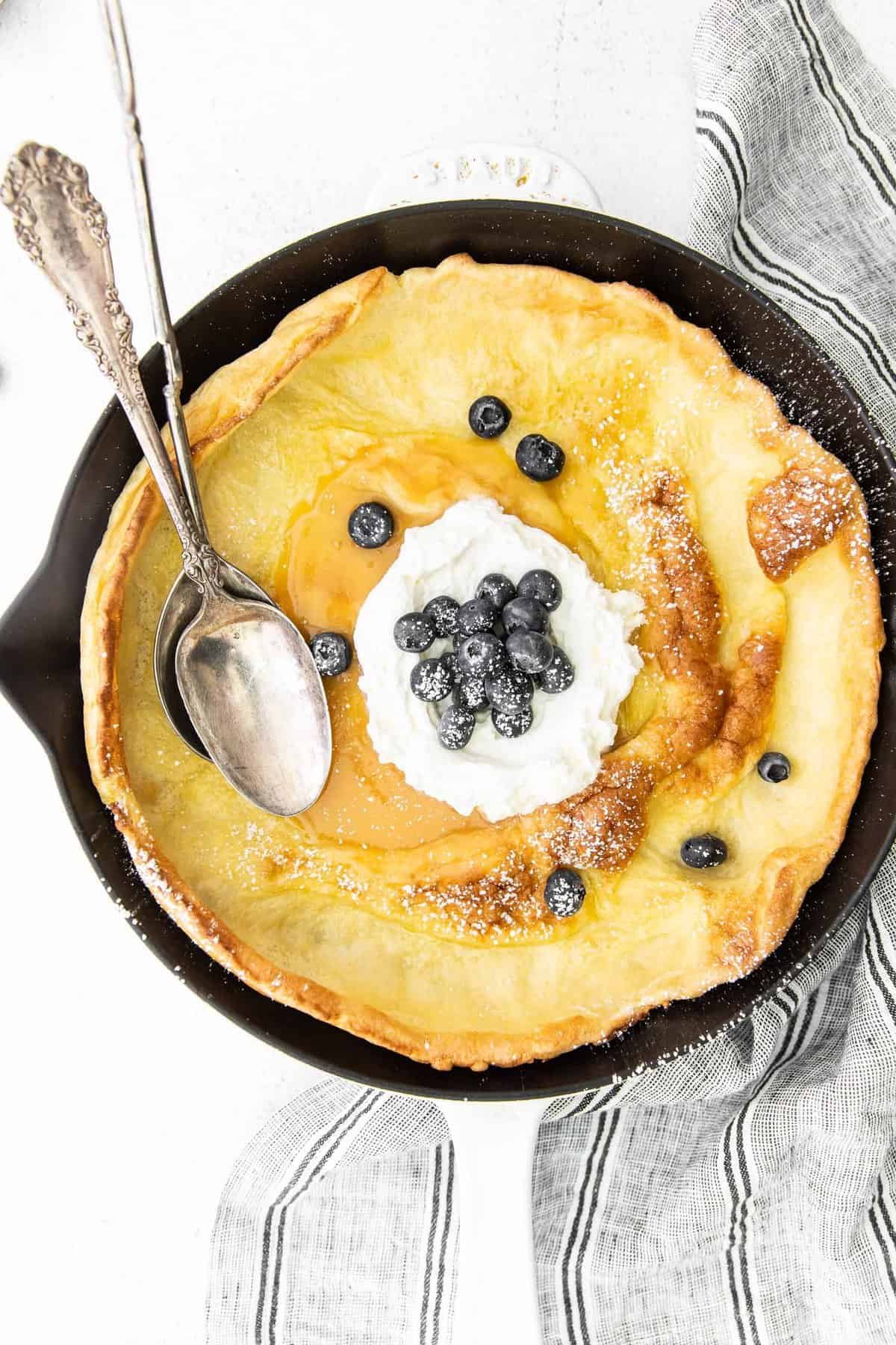 Vista aérea de uma panqueca holandesa de limão com mirtilos e chantilly.