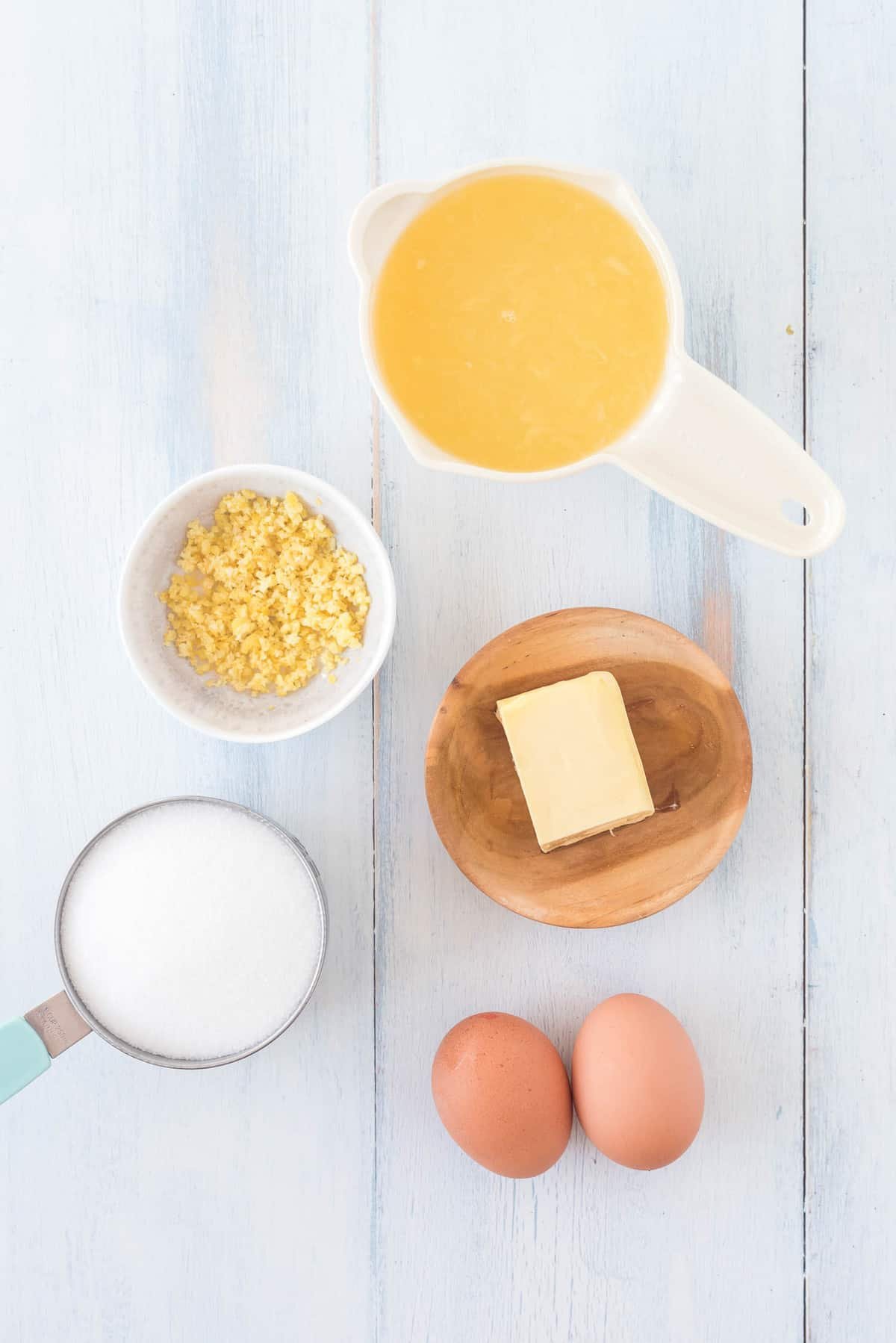 Visão aérea dos ingredientes necessários: manteiga, açúcar, suco de limão, raspas de limão, ovos.