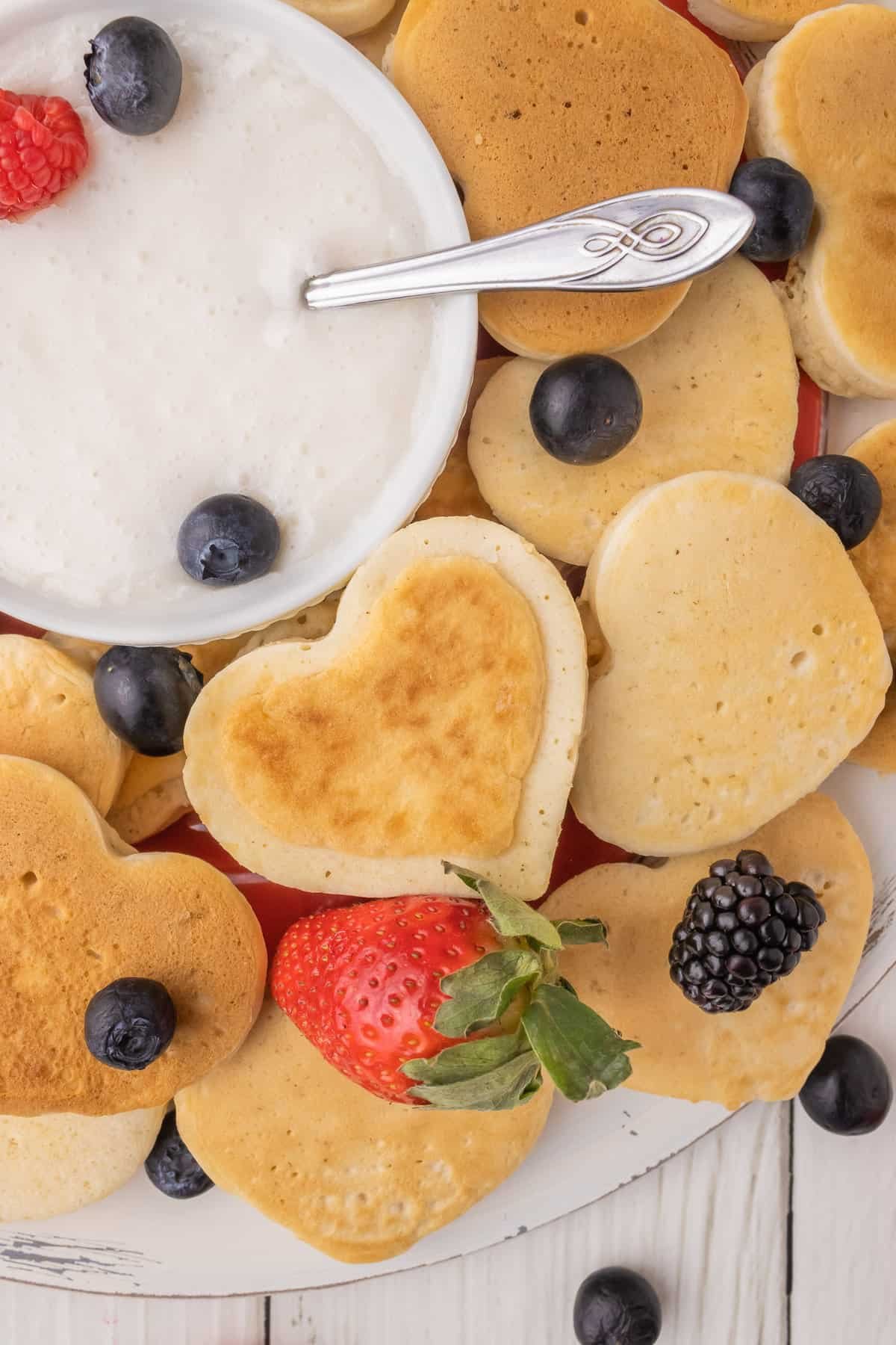 Panqueca em formato de coração ao lado de uma tigela de molho de iogurte.