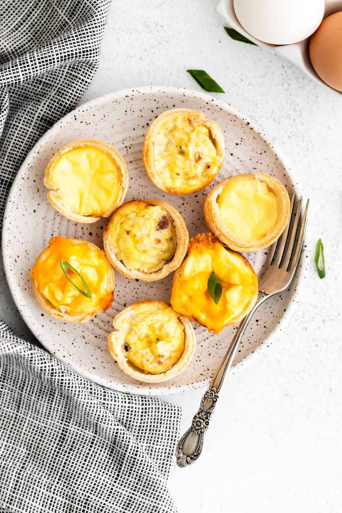 3 variedades de mini quiches em um prato redondo pequeno.
