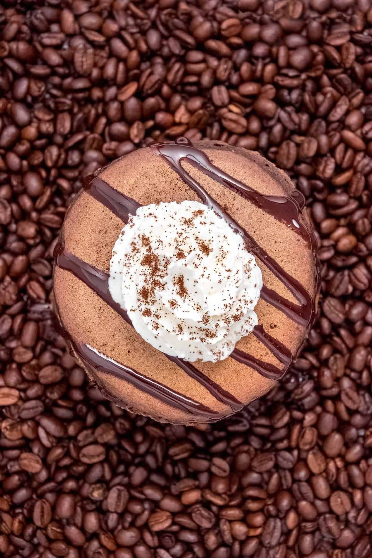 Panquecas de Chocolate, cobertas com chantilly e salpicadas com chocolate, sobre grãos de café.