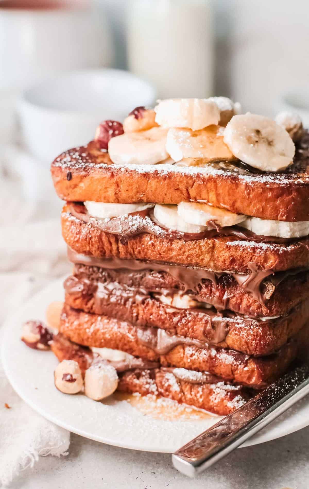 Close up de uma alta pilha de torrada francesa de Nutella com bananas.