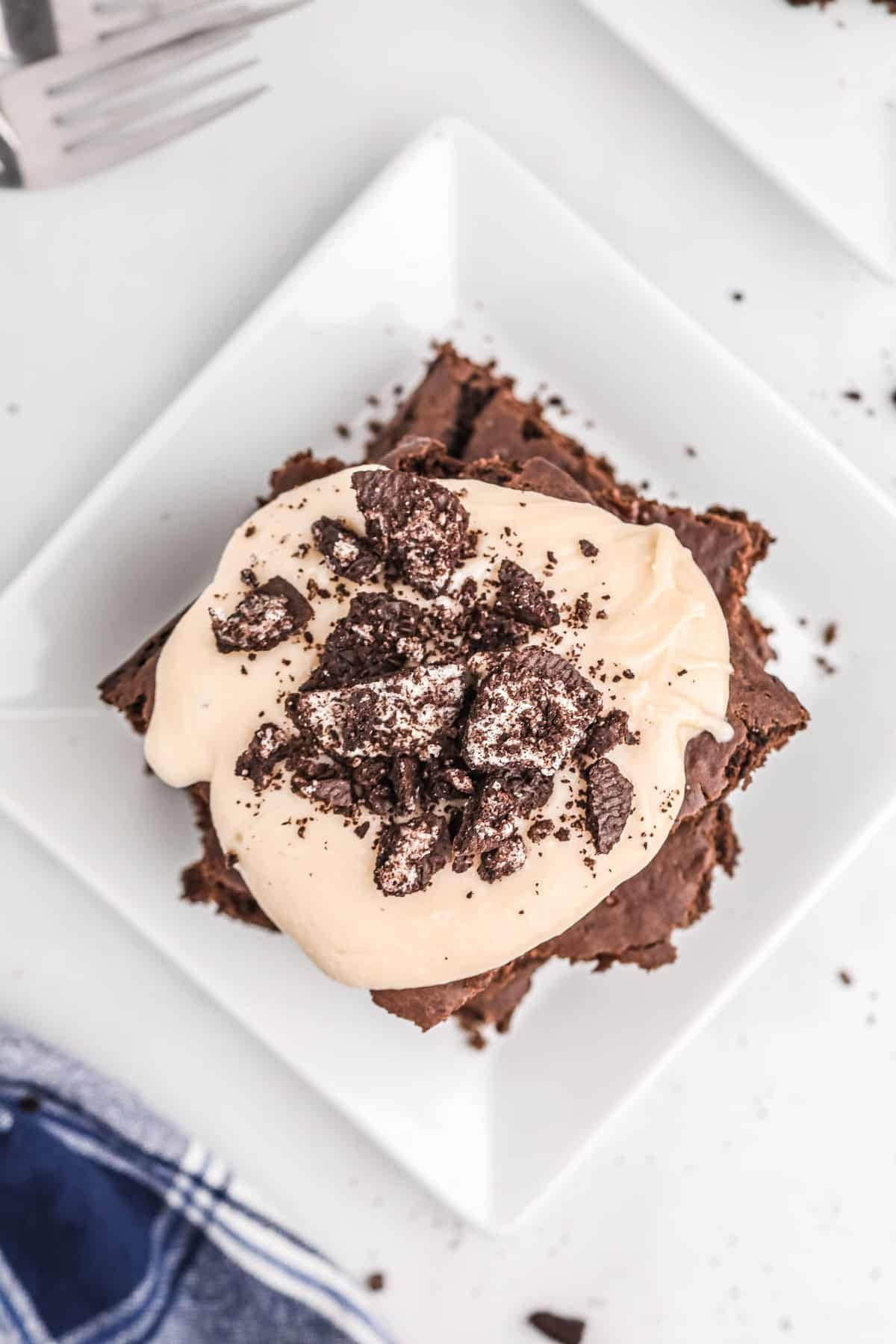 Vista aérea de panquecas quadradas de chocolate cobertas com molho cremoso e bolachas Oreo esmagadas.