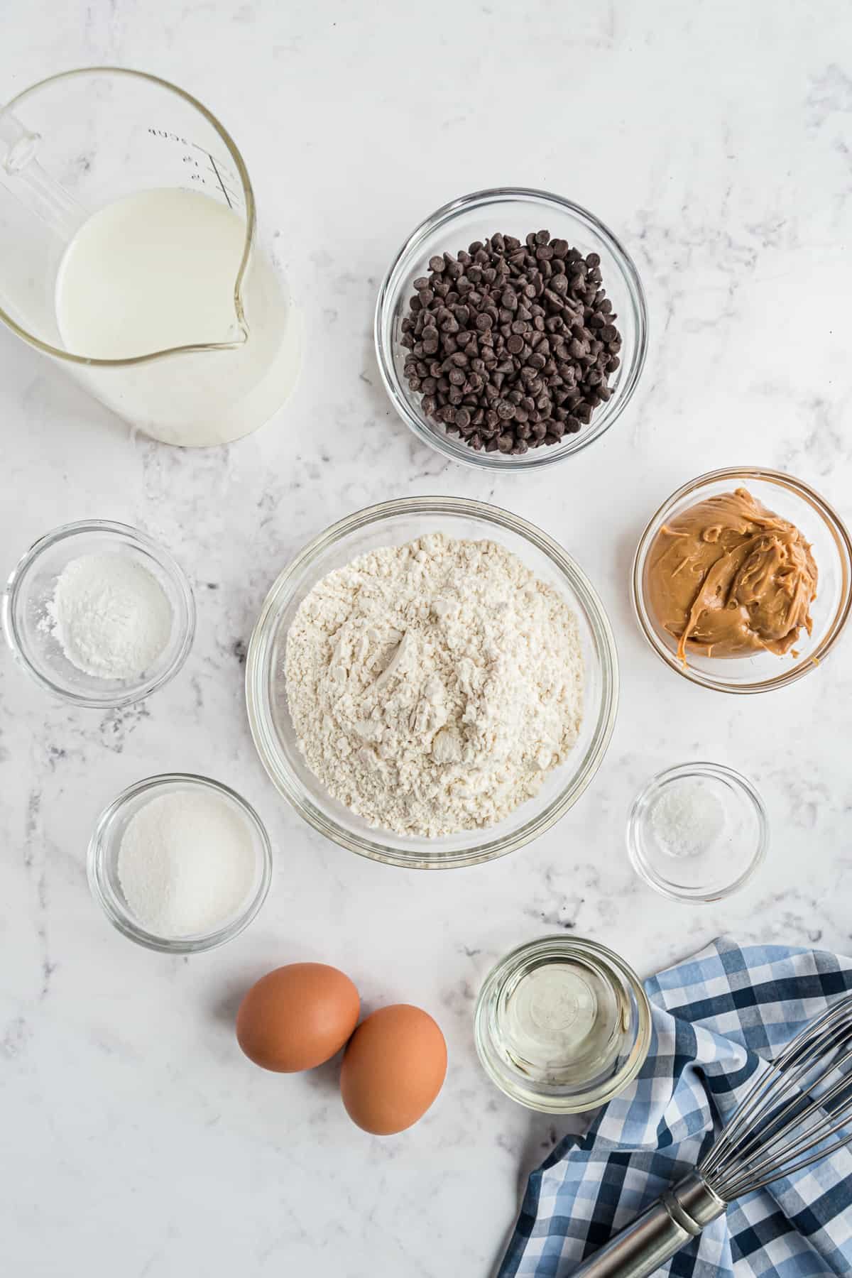 Pequenos recipientes de ingredientes, incluindo manteiga de amendoim e gotas de chocolate, e ovos marrons.