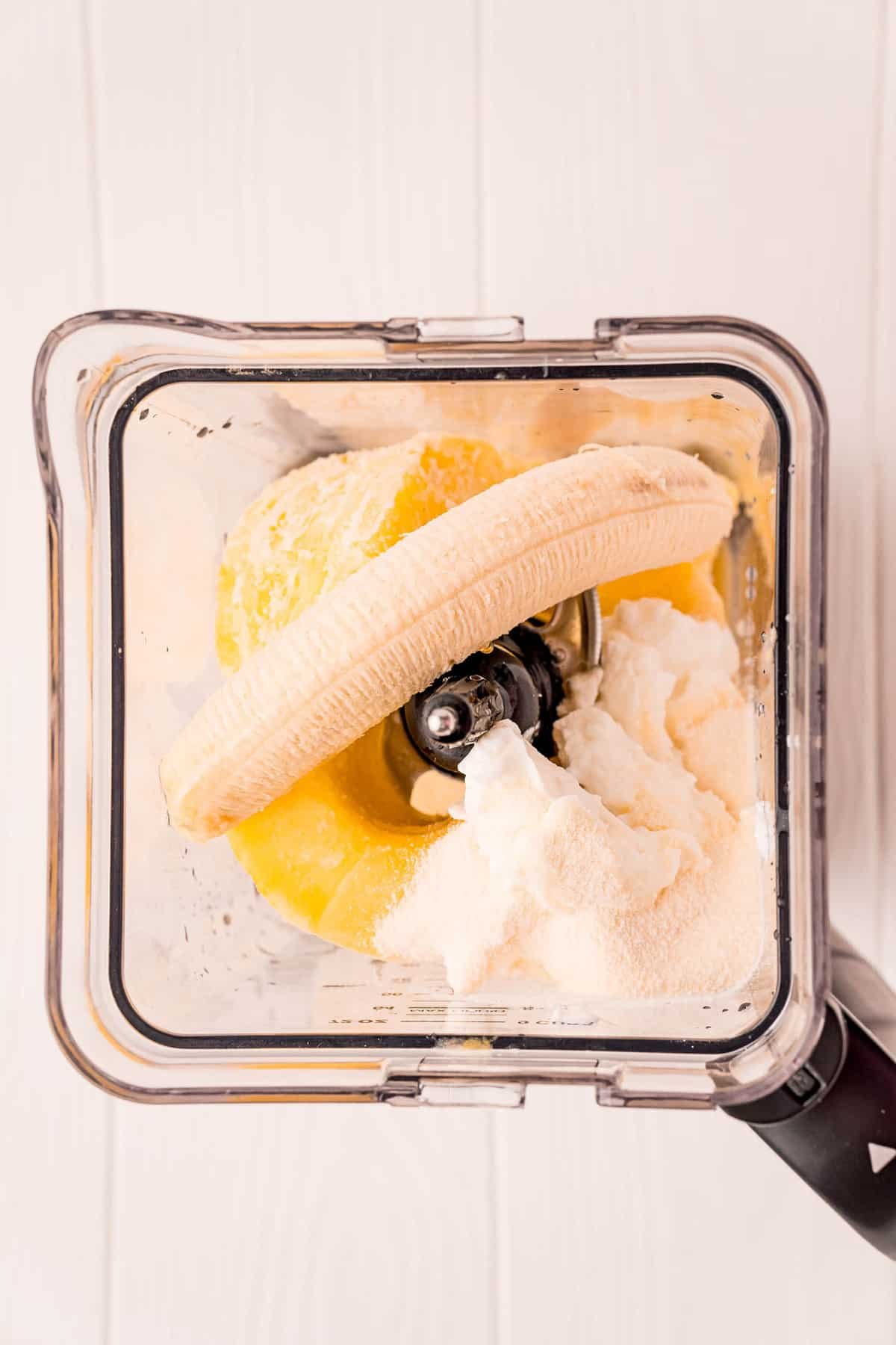 Vista aérea do liquidificador com banana, iogurte e mais.