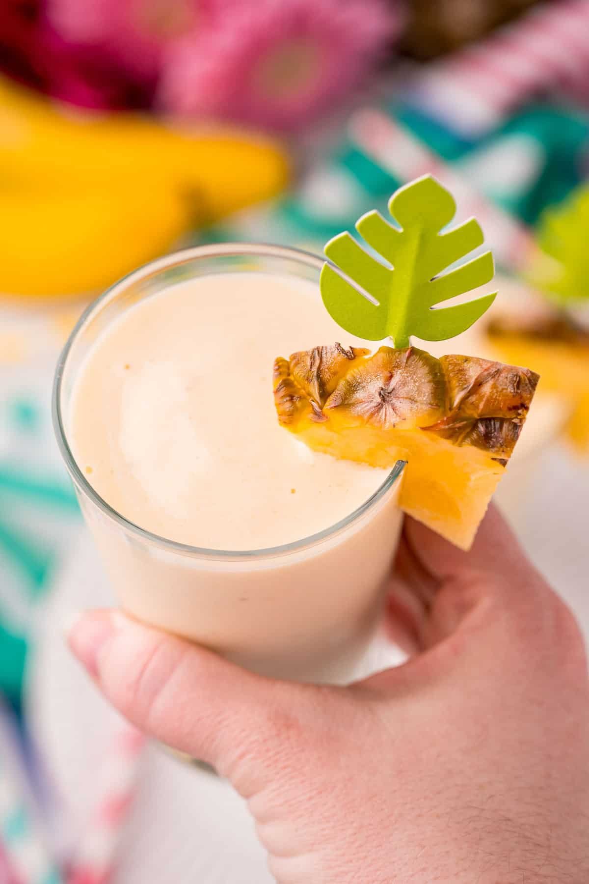 Mão segurando um batido amarelo claro.