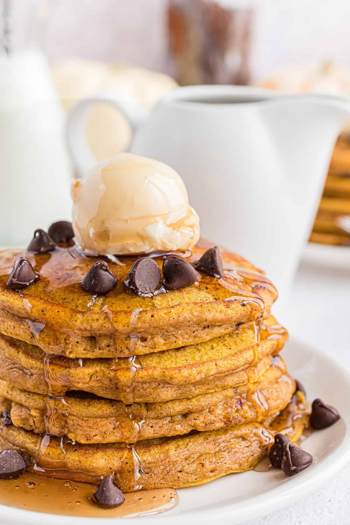 Pilha de panquecas de abóbora com gotas de chocolate, manteiga e xarope.
