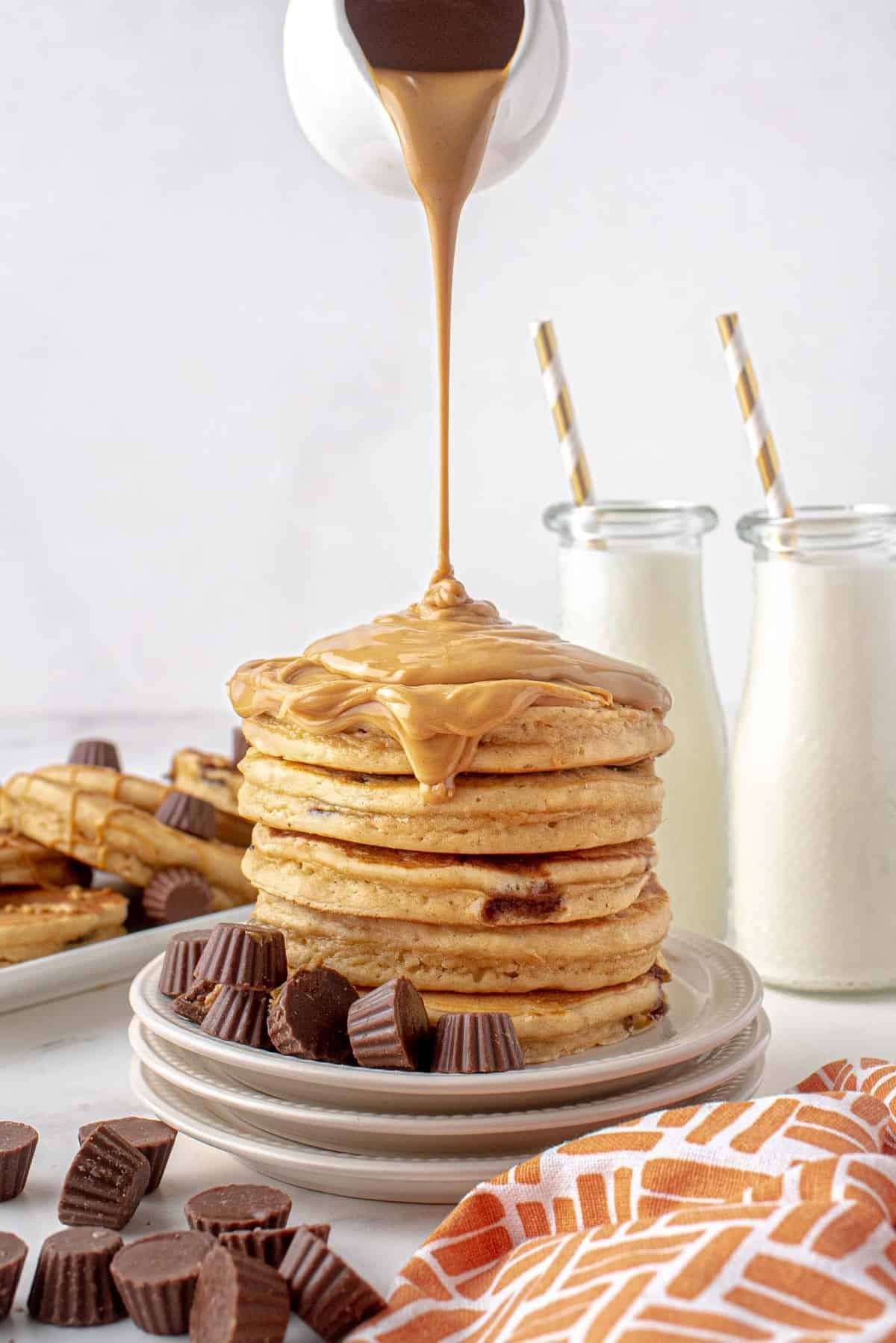 Manteiga de amendoim derretida sendo despejada em uma pilha de panquecas.