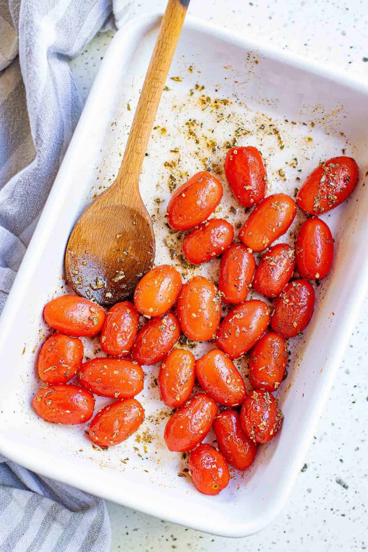 Tomates e temperos em um prato de cozimento branco.