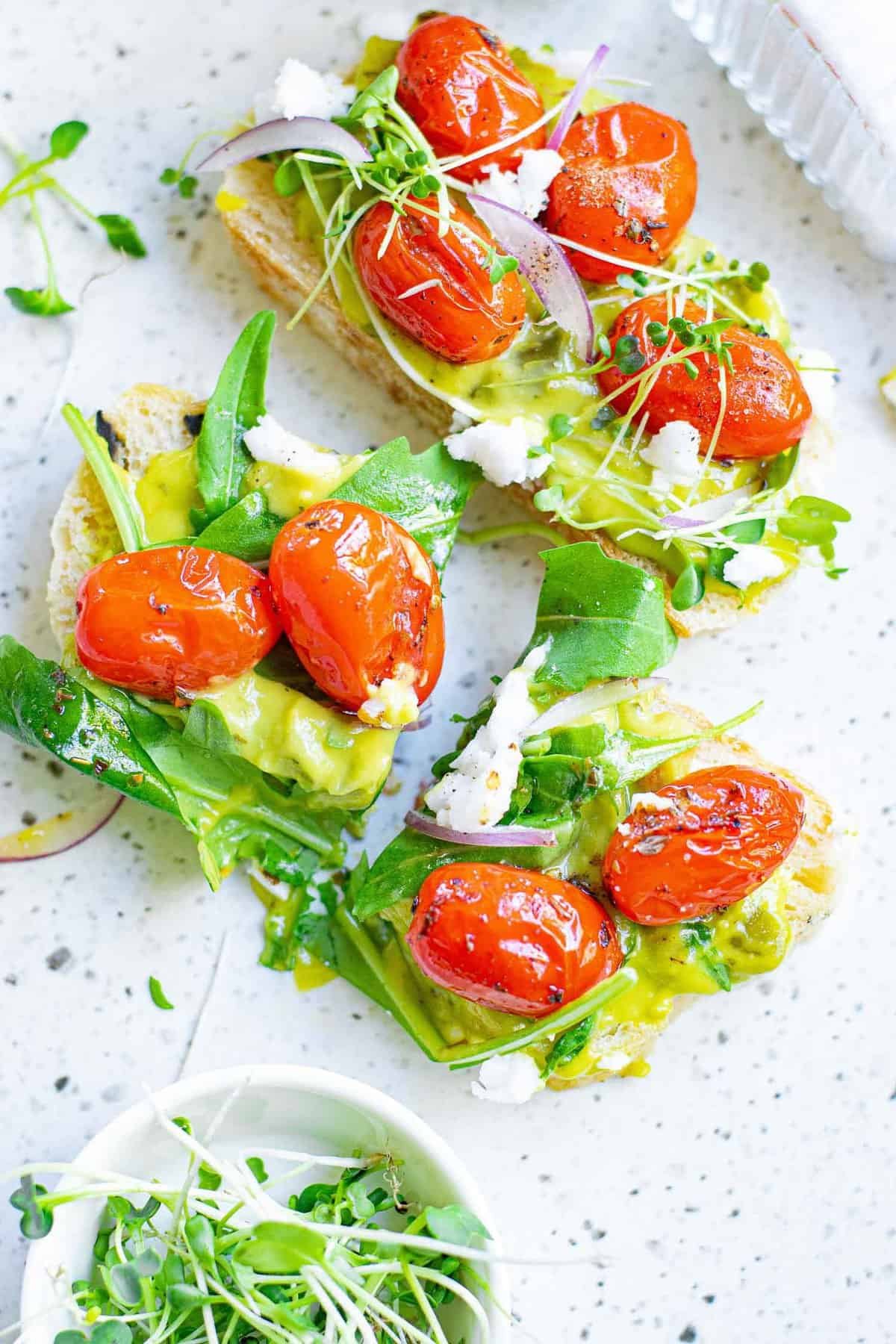 Torrada com guacamole, tomates, feta e folhas verdes. 