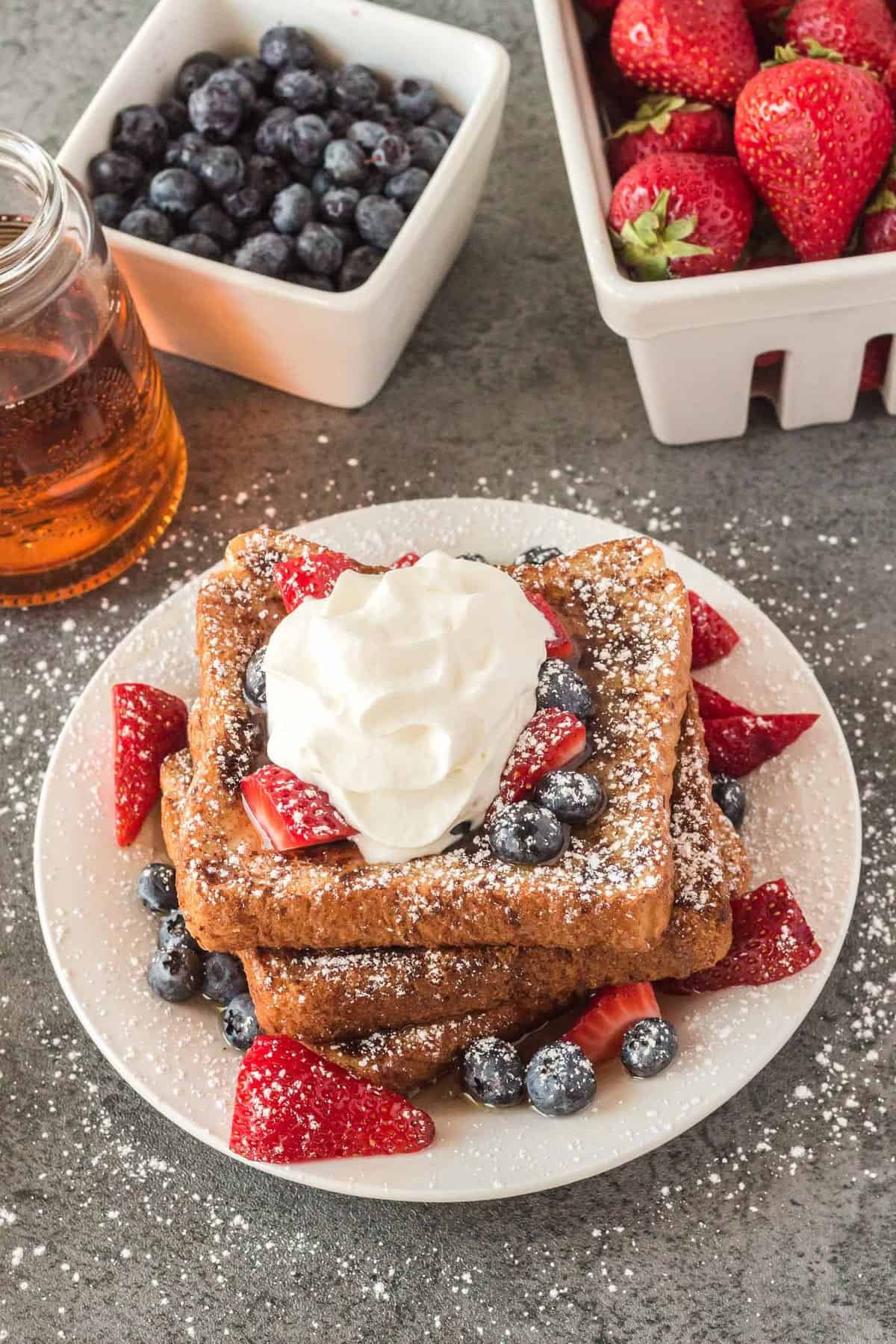 Torrada francesa em forma de assado em um prato com frutas vermelhas.