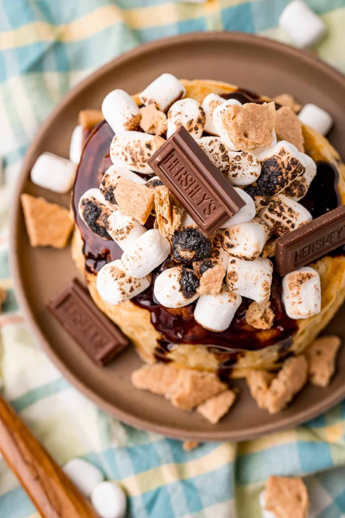 Visão aérea de panquecas cobertas com chocolate, biscoito de graham, marshmallows.