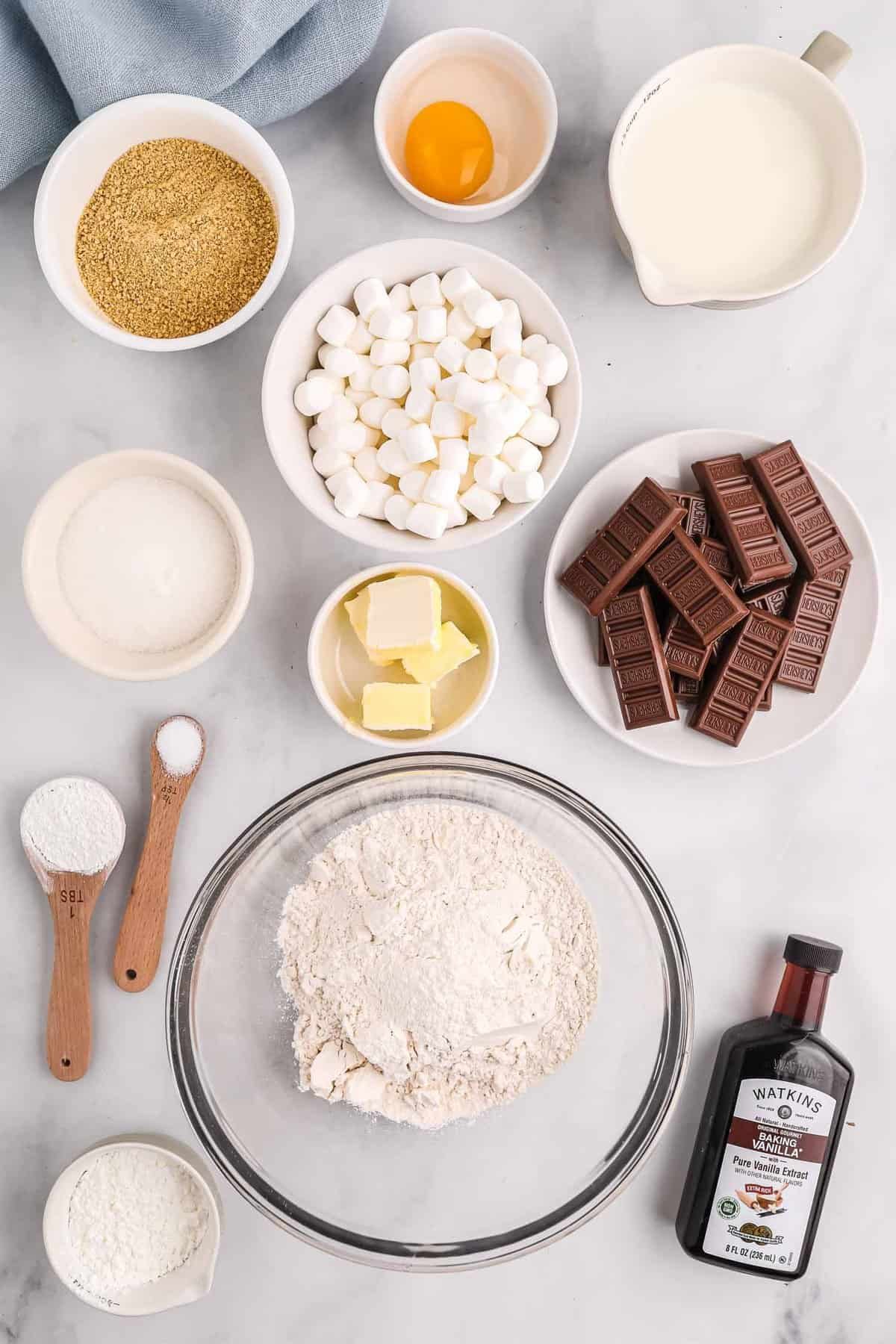 Vista aérea dos ingredientes necessários para fazer panquecas de folha, incluindo barras de chocolate, marshmallows e migalhas de biscoito de graham.