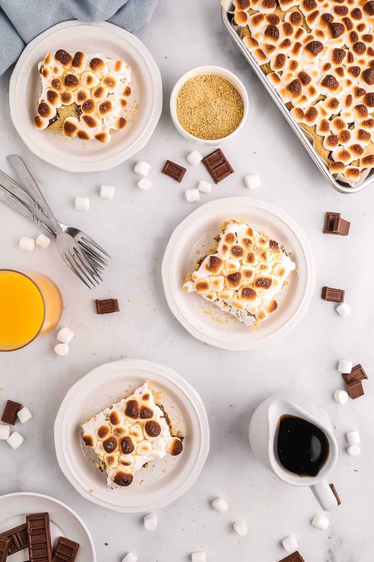 Vista aérea de três pratos de panquecas de s'mores com uma folha de mais visível também.