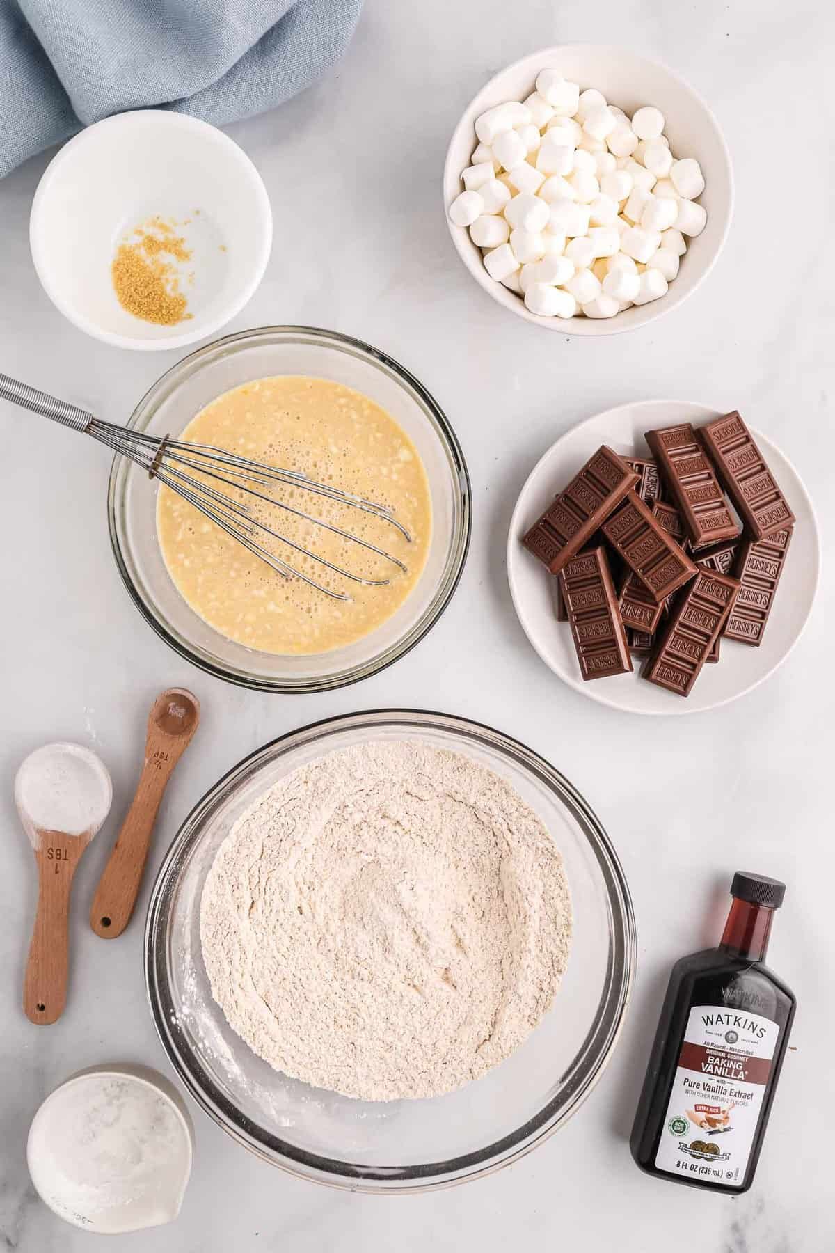 Ingredientes secos misturados em uma tigela, outros ingredientes também visíveis.