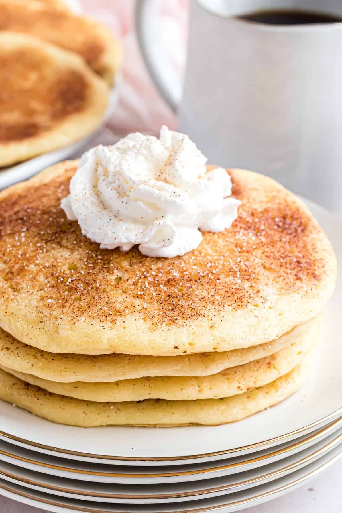 Panquecas de snickerdoodle num prato branco, cobertas com chantilly.