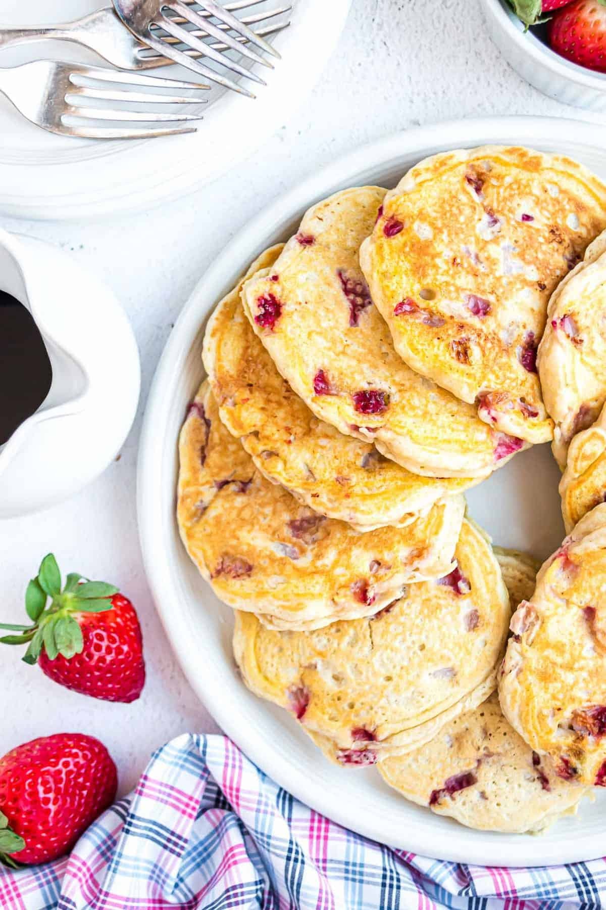 Visão aérea de panquecas de morango em um prato branco.