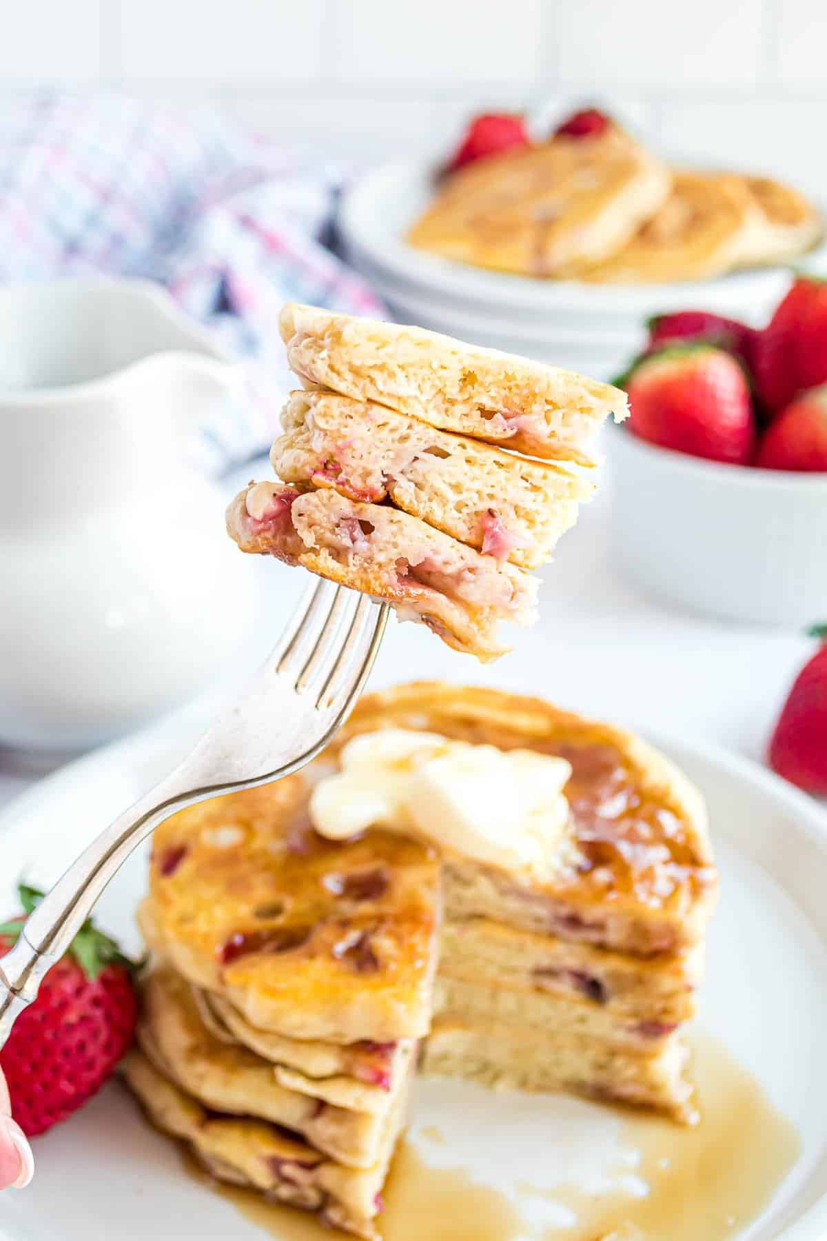 Panquecas com morangos em um garfo.